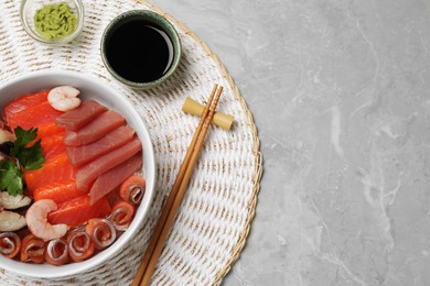 Photo of Delicious mackerel, shrimps, salmon and tuna served with parsley, wasabi and soy sauce on grey marble table, top view with space for text. Tasty sashimi dish