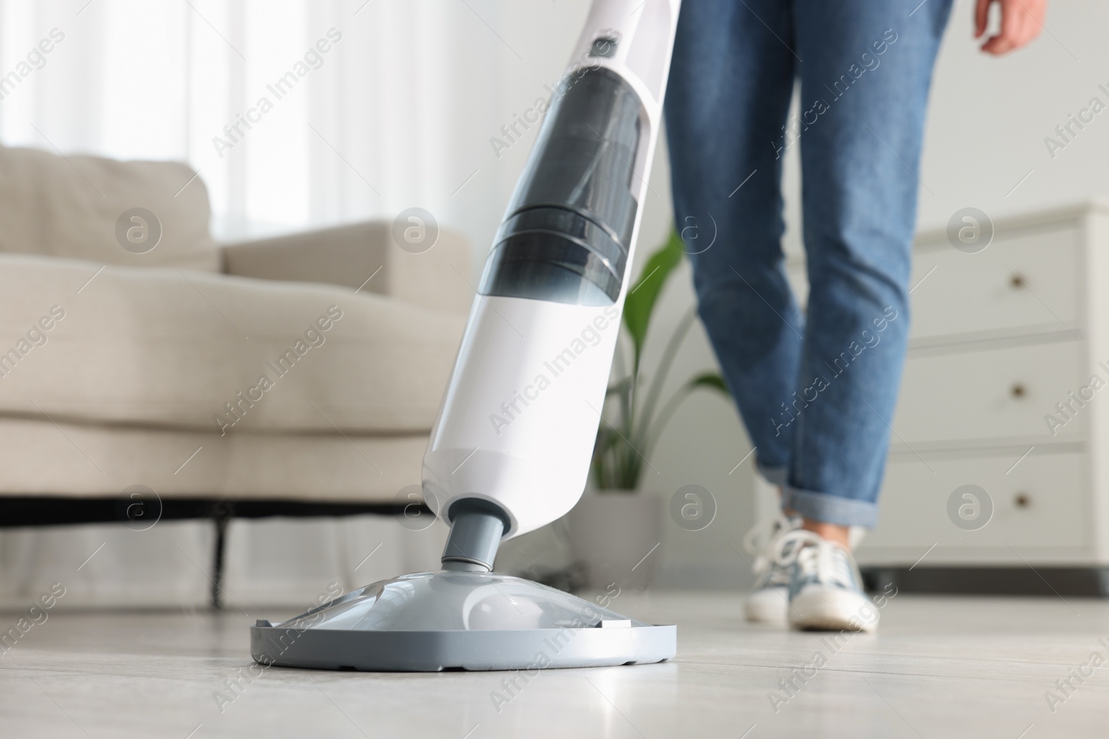 Photo of Woman cleaning floor with steam mop at home, closeup