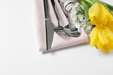 Photo of Cutlery set, Easter eggs and beautiful flowers on white background, space for text. Festive table setting