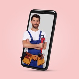 Plumber looking out of smartphone on pink background