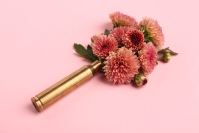 Beautiful flowers in bullet case on pink background, closeup