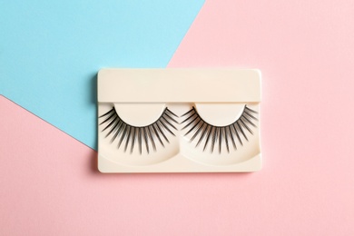 False eyelashes on color background, top view