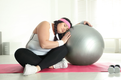 Photo of Lazy overweight woman leaning fit ball at gym