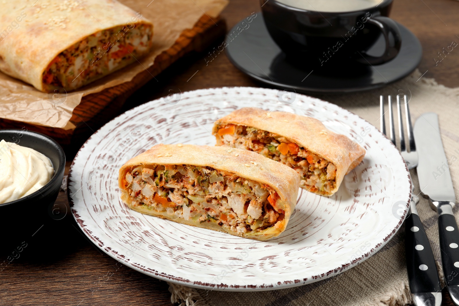 Photo of Pieces of delicious strudel with chicken and vegetables served on wooden table