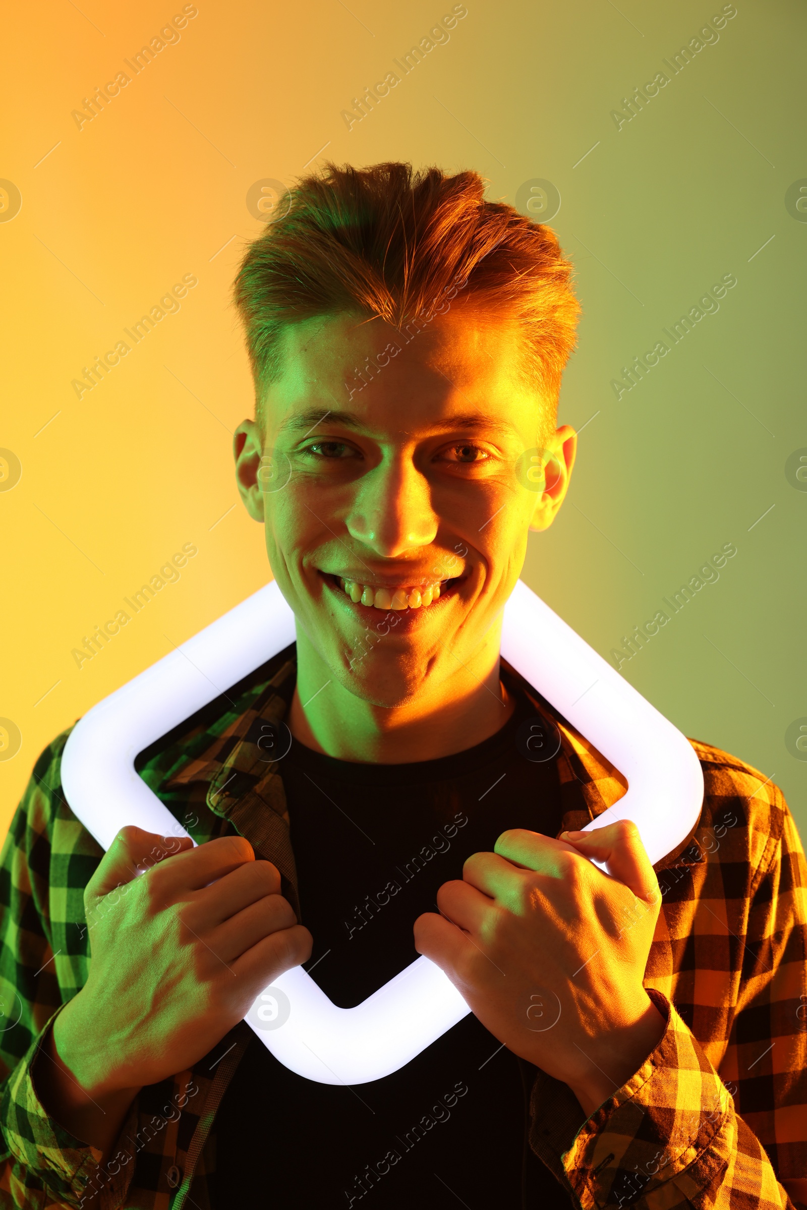 Photo of Young man with square lamp on color background in neon lights