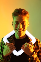 Photo of Young man with square lamp on color background in neon lights