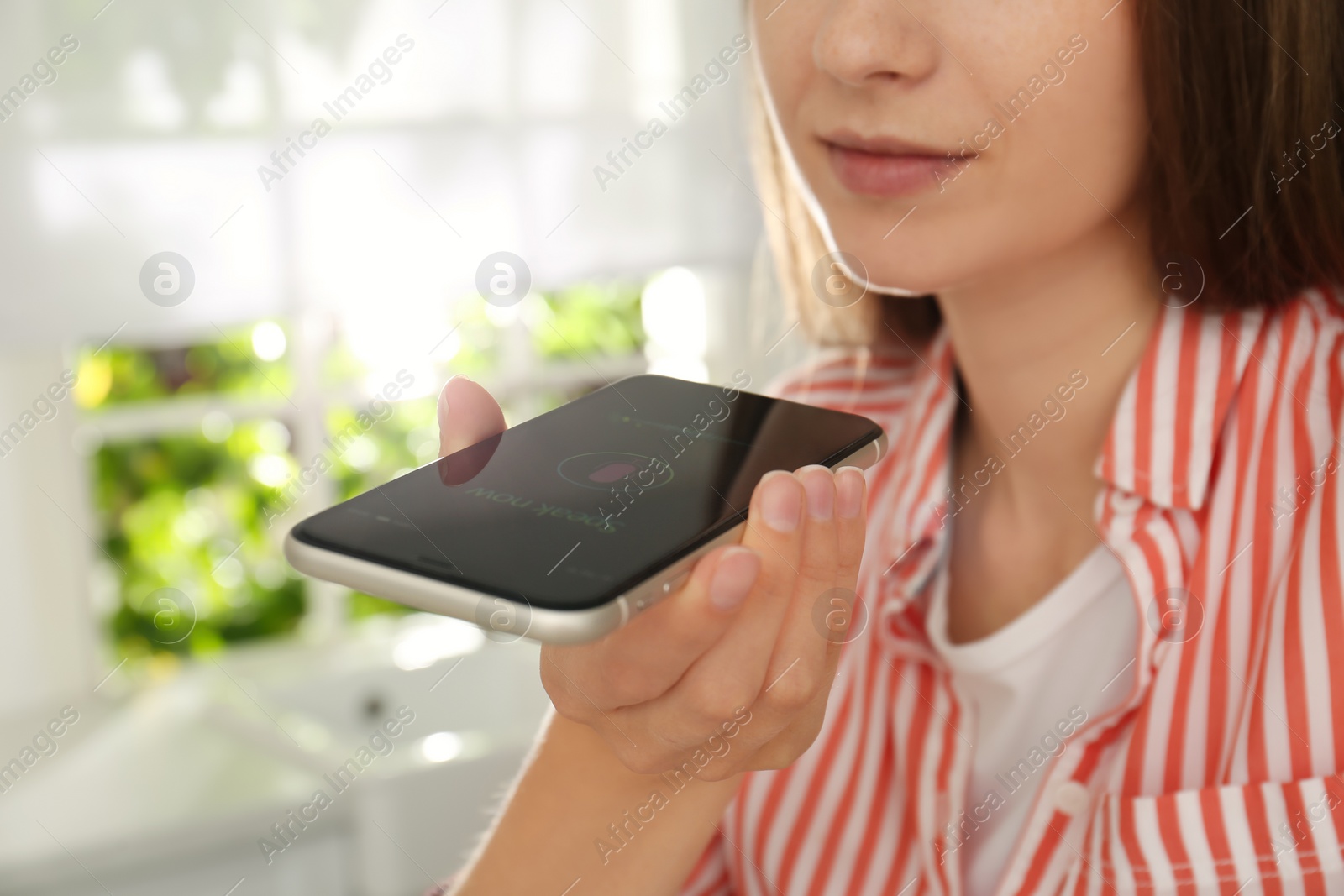 Photo of Woman using voice search on smartphone indoors, closeup