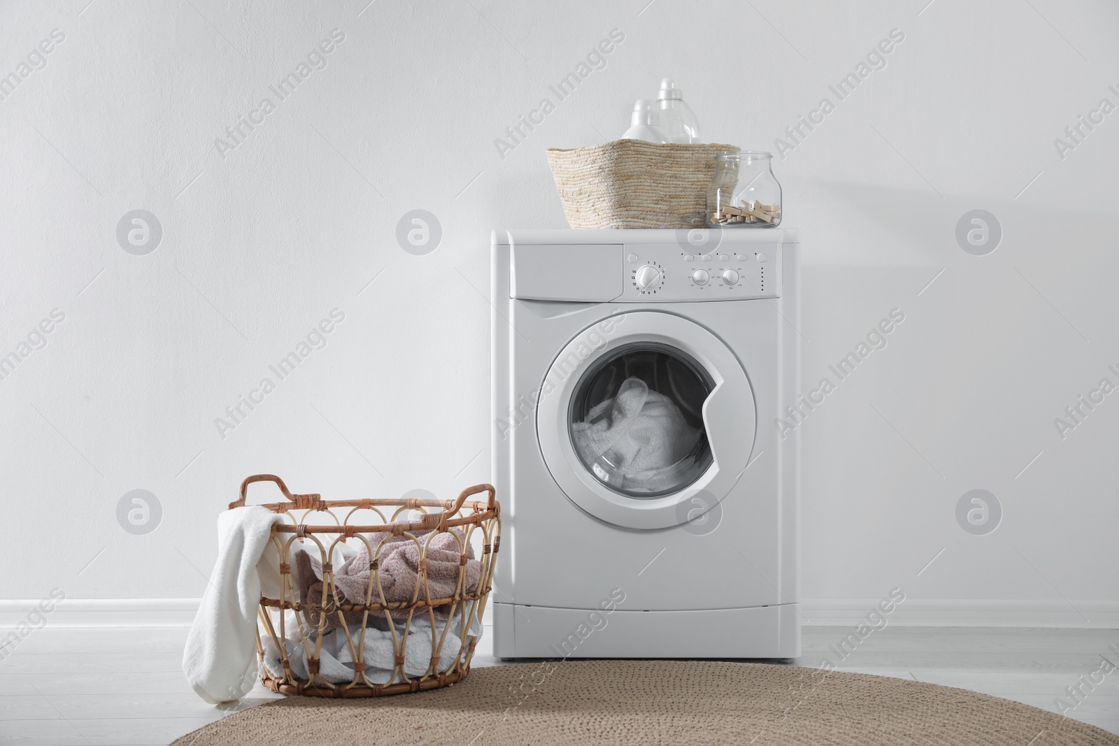 Photo of Modern washing machine and laundry baskets near white wall indoors. Bathroom interior