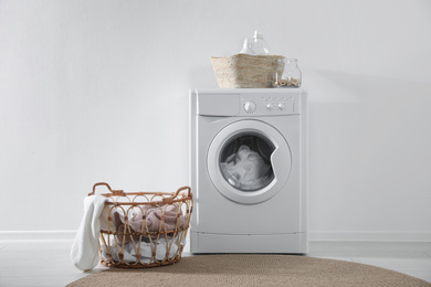 Modern washing machine and laundry baskets near white wall indoors. Bathroom interior