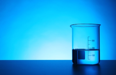 Photo of Empty beaker on table against color background. Chemistry laboratory glassware