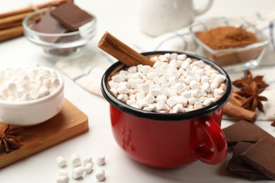 Photo of Tasty hot chocolate with marshmallows and ingredients on white table, closeup