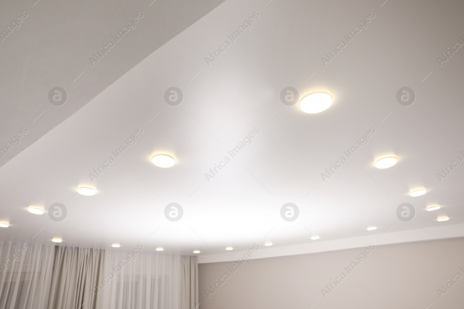 Photo of White stretch ceiling with spot lights in room