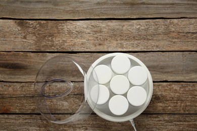 Modern yogurt maker with jars on wooden table, top view. Space for text