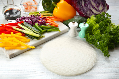 Photo of Dry rice paper and ingredients on white wooden table