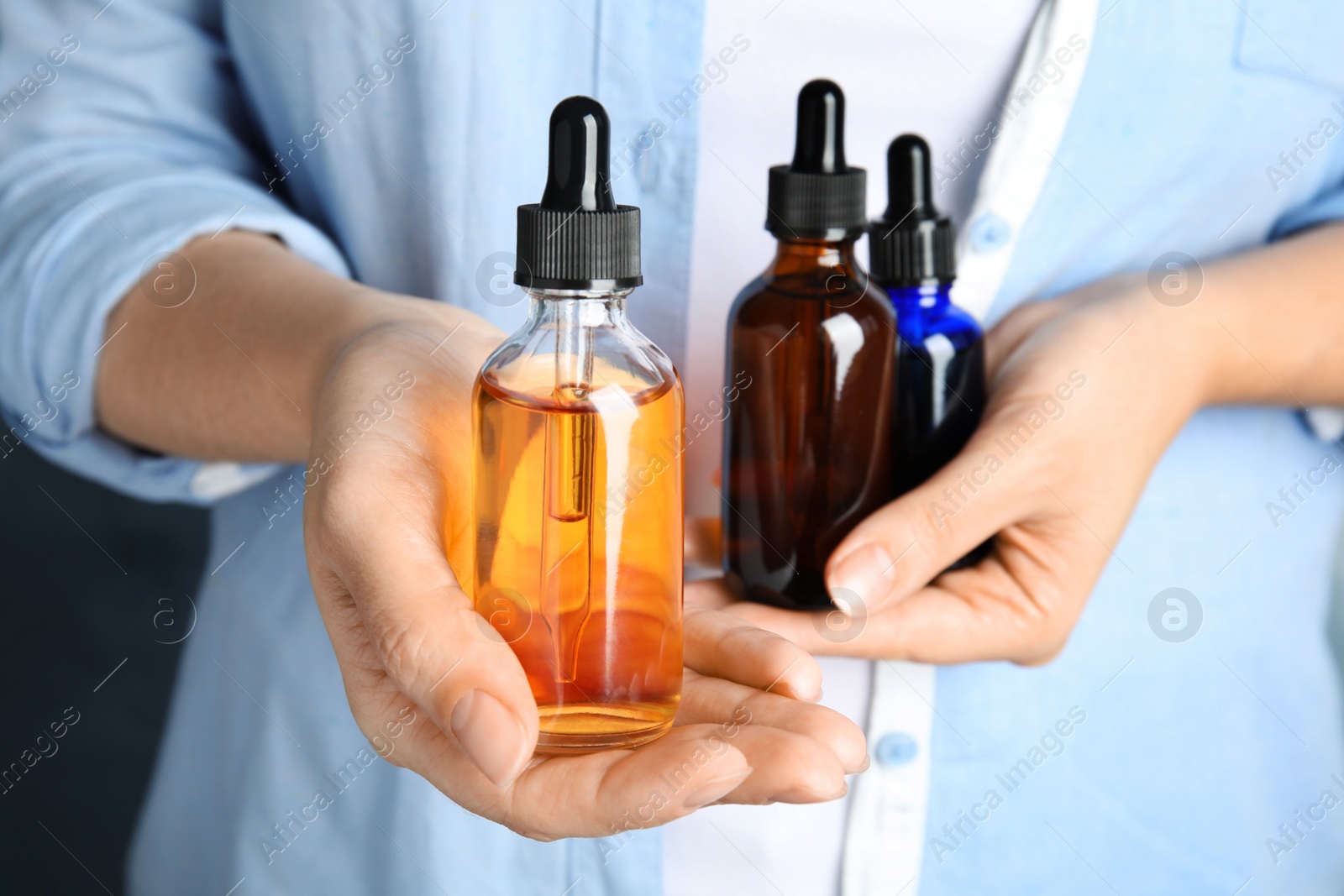 Photo of Woman holding different bottles with essential oils, closeup