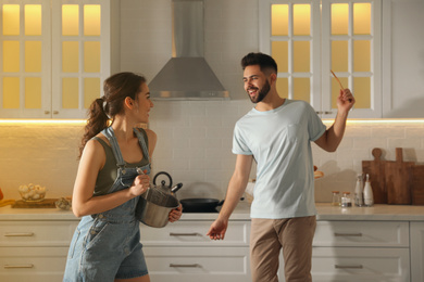 Lovely young couple dancing while cooking together in kitchen