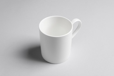 Photo of One white ceramic mug on light background