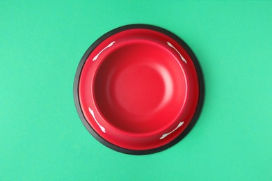 Empty red feeding bowl on green background, top view