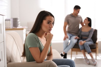 Photo of Unhappy woman feeling jealous while couple spending time together at home