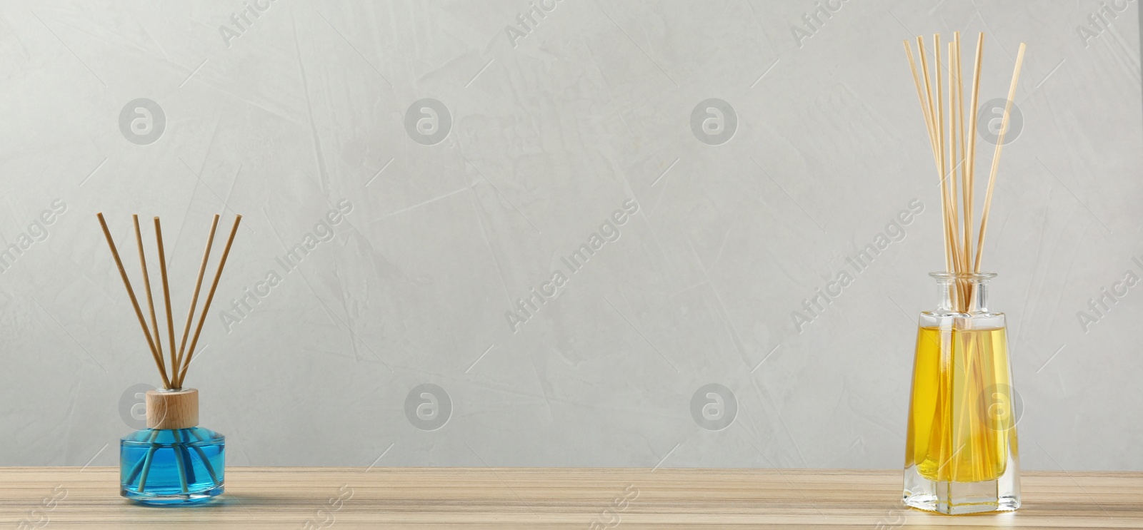 Photo of Reed air fresheners on wooden table against grey background, space for text