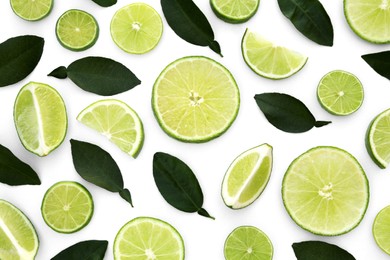 Photo of Fresh cut limes with leaves on white background, flat lay