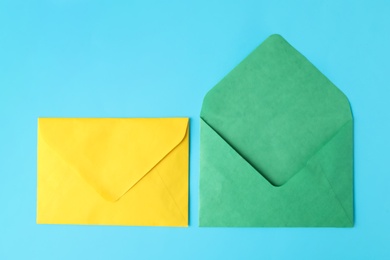 Photo of Colorful paper envelopes on light blue background, flat lay