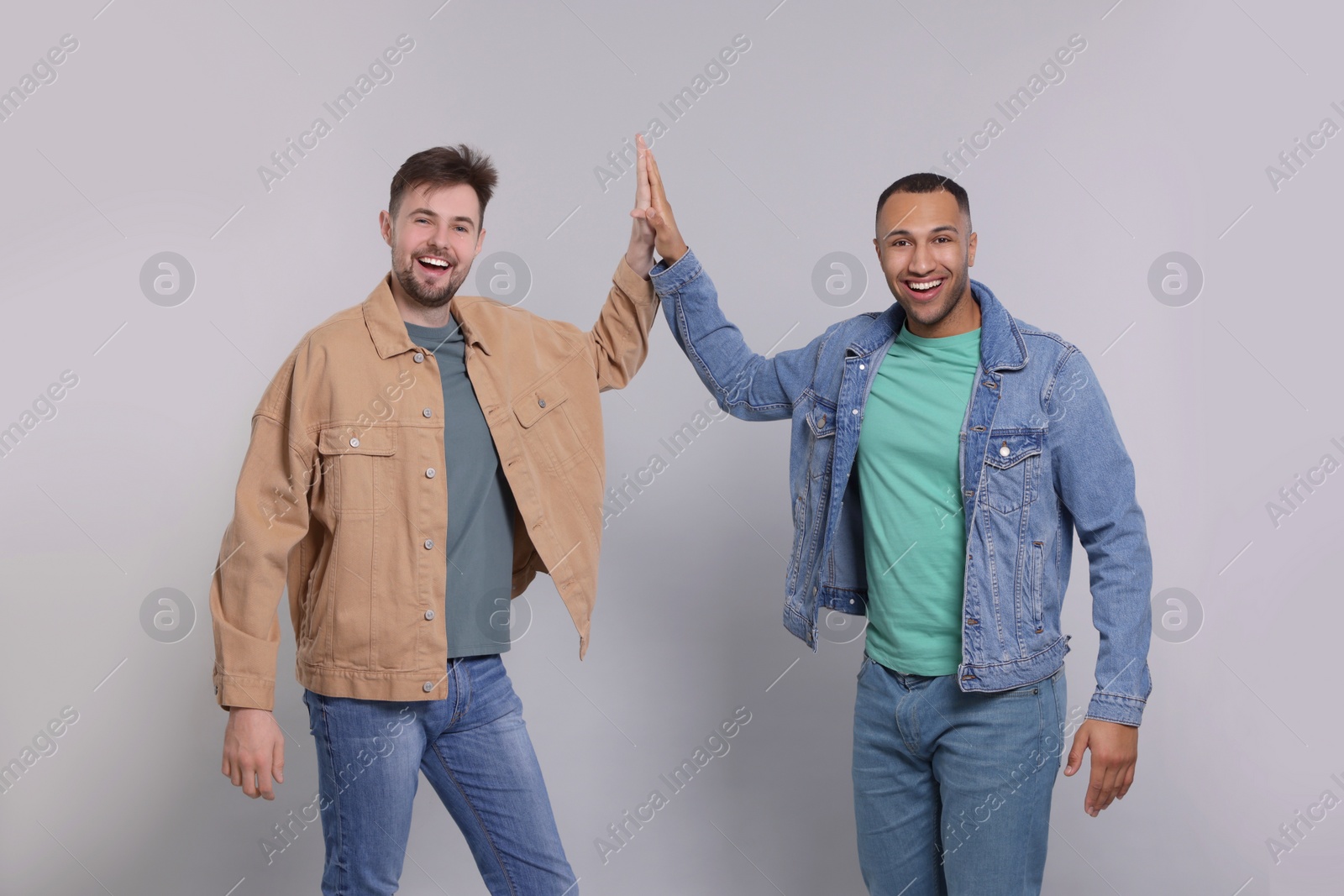 Photo of Men giving high five on grey background
