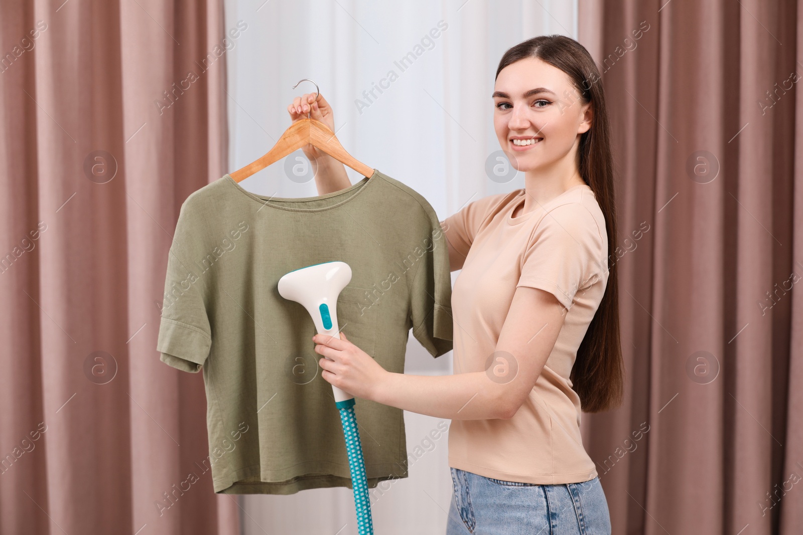 Photo of Woman steaming shirt on hanger at home