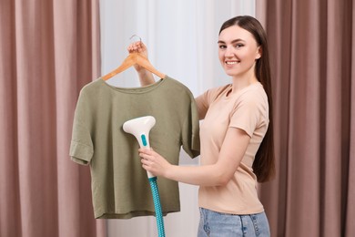 Photo of Woman steaming shirt on hanger at home