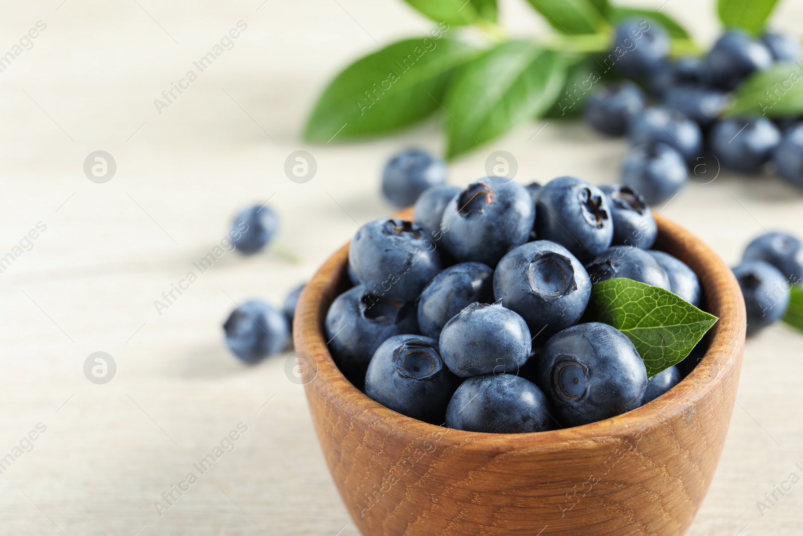 Photo of Bowl of fresh tasty blueberries on table, closeup. Space for text