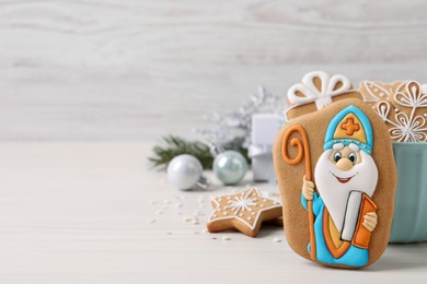 Photo of Tasty gingerbread cookies and festive decor on white wooden table, space for text. St. Nicholas Day celebration