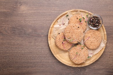 Tasty vegan cutlets with breadcrumbs and spices on wooden table, top view. Space for text