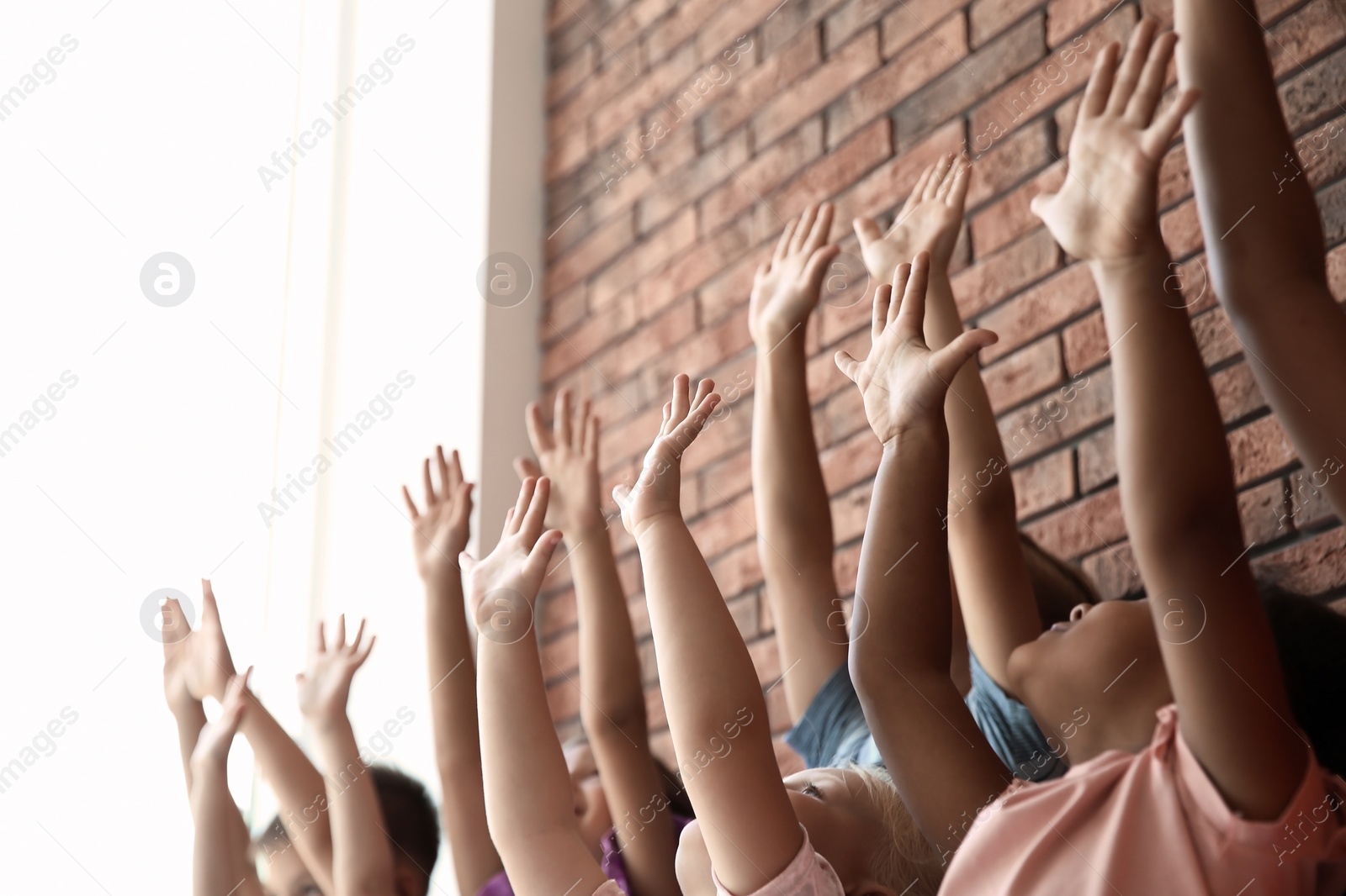 Photo of Little children raising hands together indoors. Unity concept