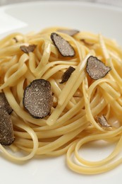 Photo of Tasty fettuccine with truffle on plate, closeup