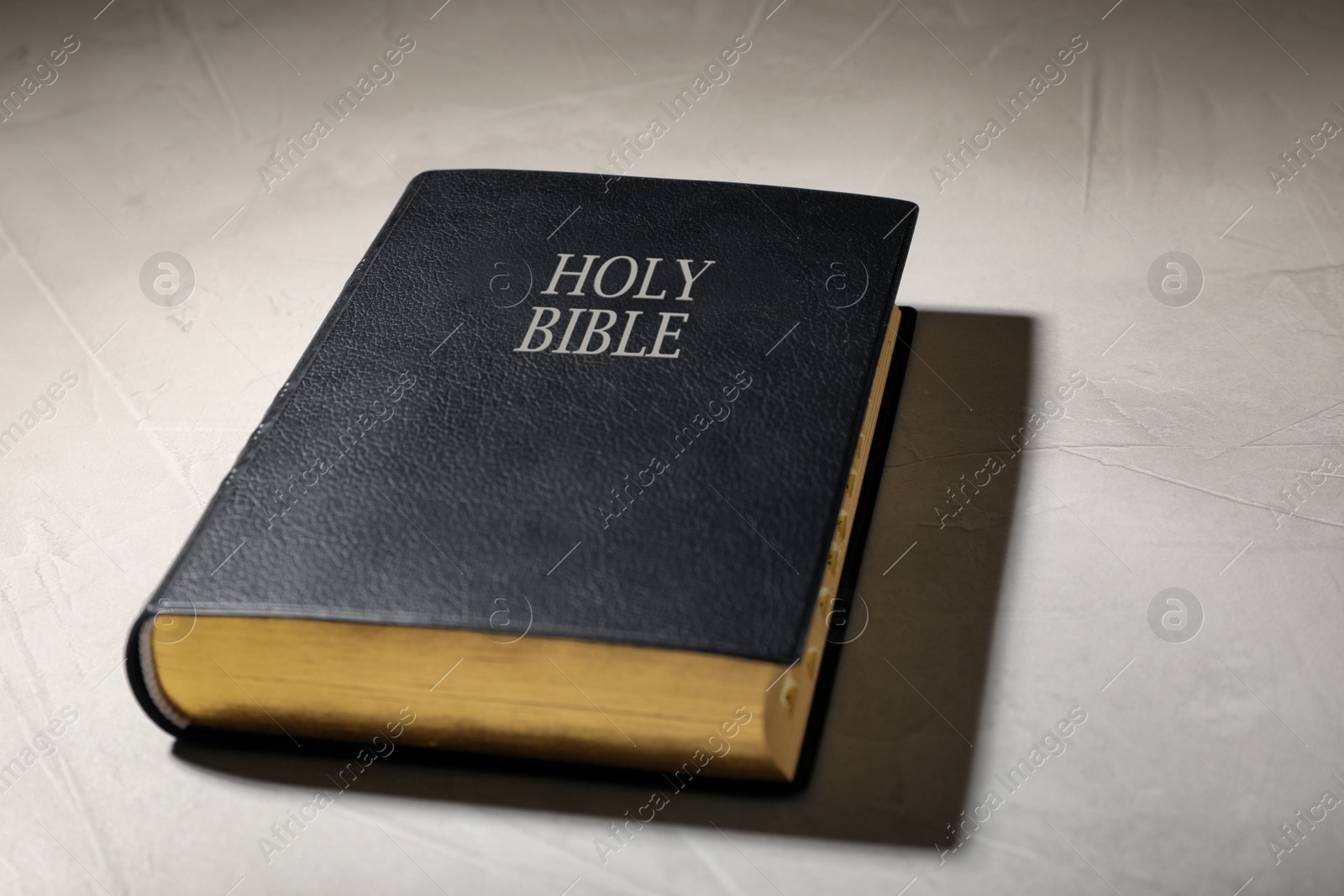 Photo of Old hardcover Bible on grey table. Religious book