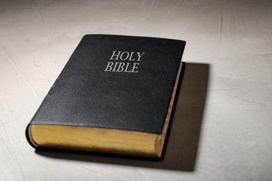 Photo of Old hardcover Bible on grey table. Religious book