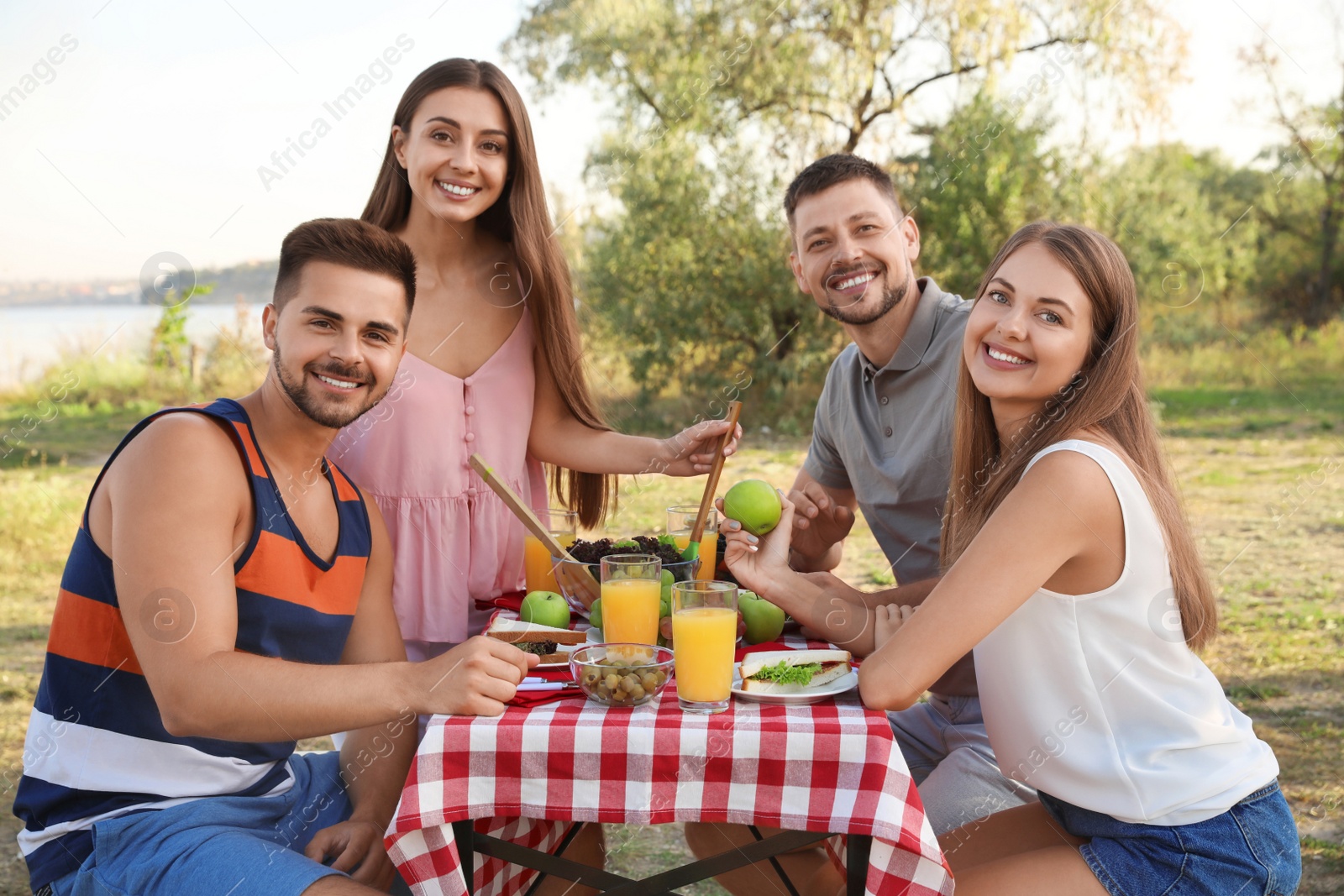 Photo of Happy young people having picnic at table in park