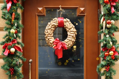 Photo of Beautiful Christmas wreath made of wine corks hanging on wooden door