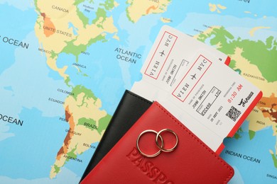 Photo of Honeymoon concept. Plane tickets, passports and golden rings on world map, top view