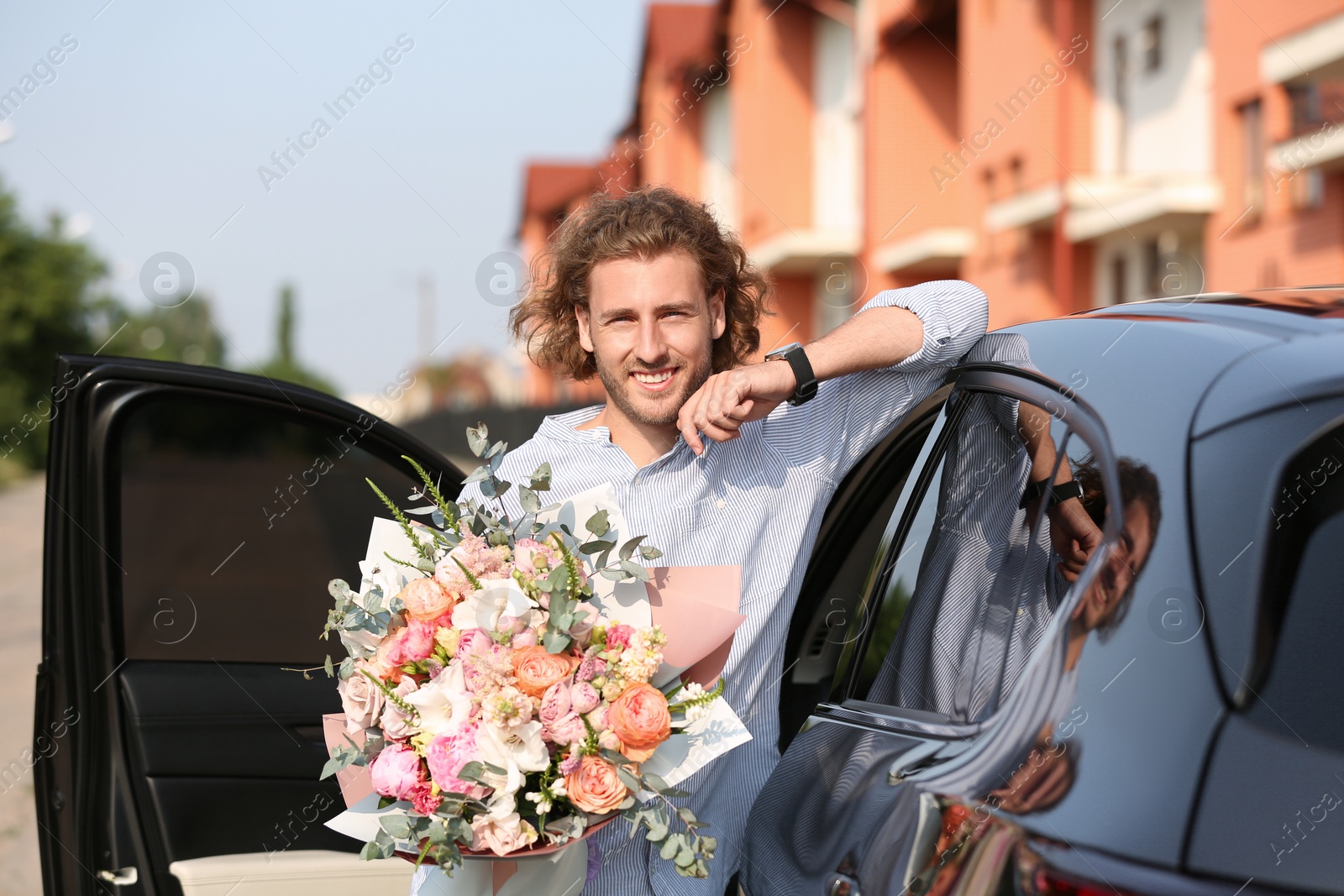 Photo of Young handsome man with beautiful flower bouquet near car on street