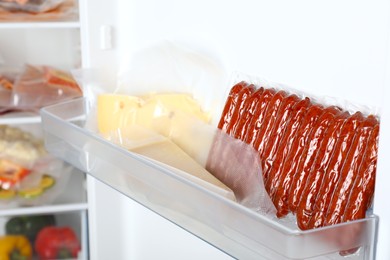 Photo of Vacuum bags with cheese and sausages in fridge, space for text. Food storage