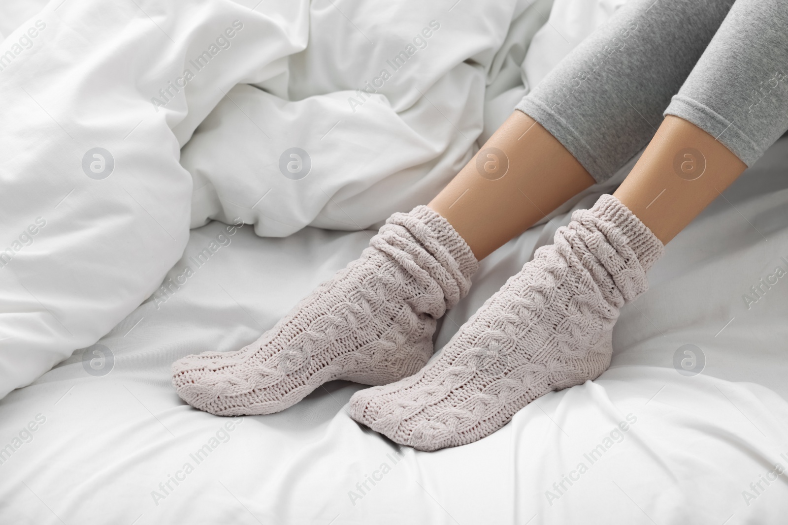 Photo of Woman wearing warm socks in comfortable bed, closeup