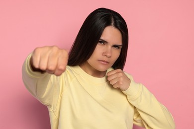 Photo of Young woman ready to fight on pink background