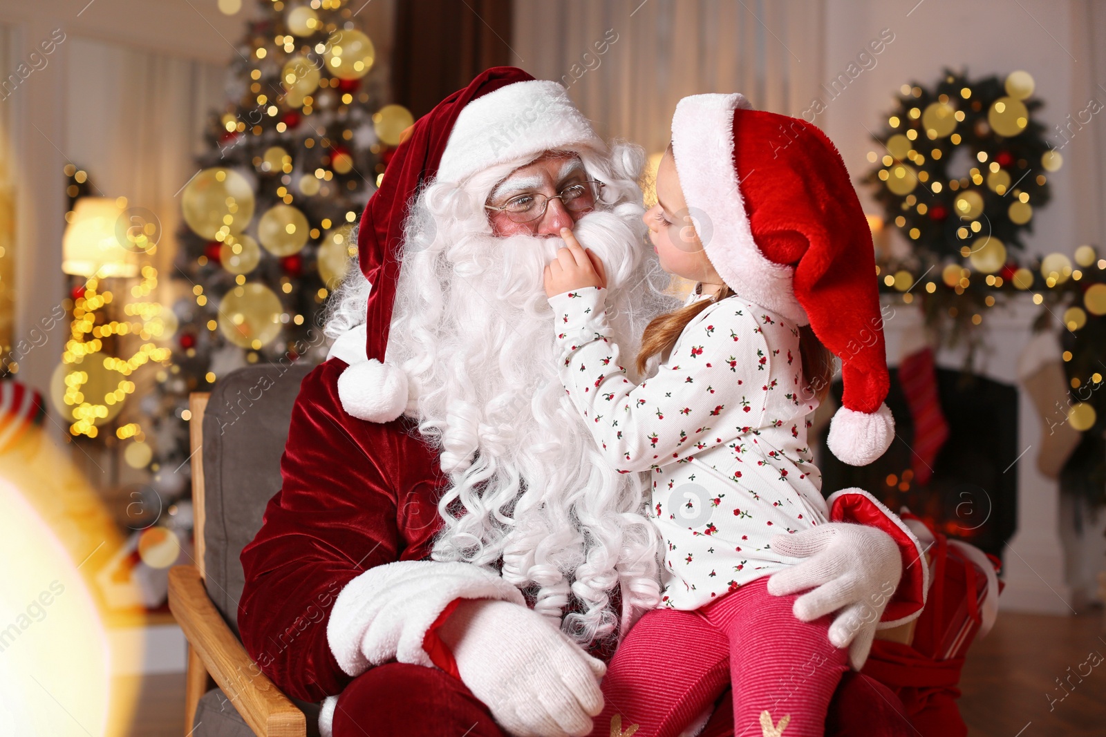 Photo of Santa Claus and cute little girl in room decorated for Christmas