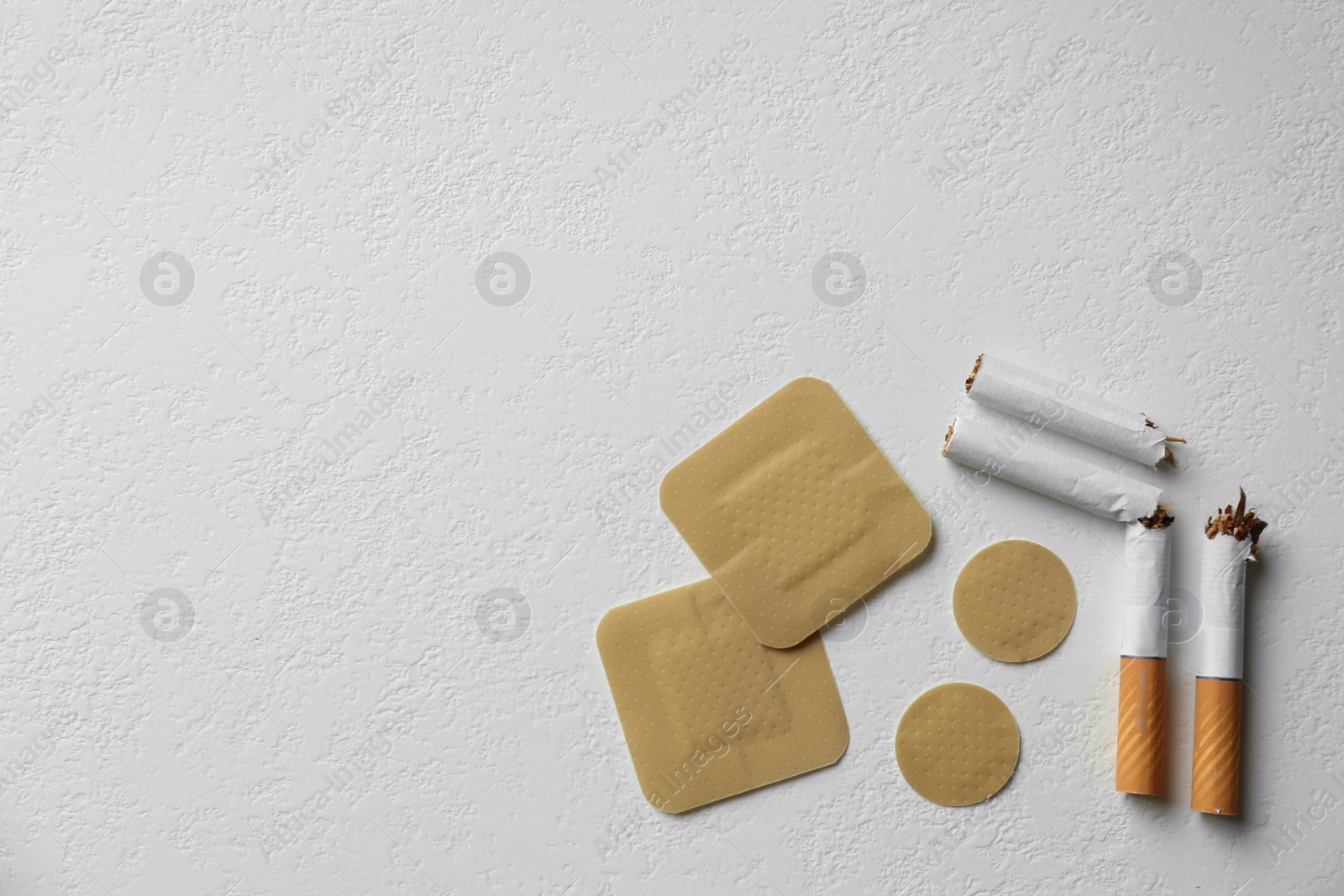 Photo of Nicotine patches and broken cigarettes on white background, flat lay. Space for text