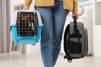 Travel with pet. Woman holding carrier with dog and backpack at home, closeup