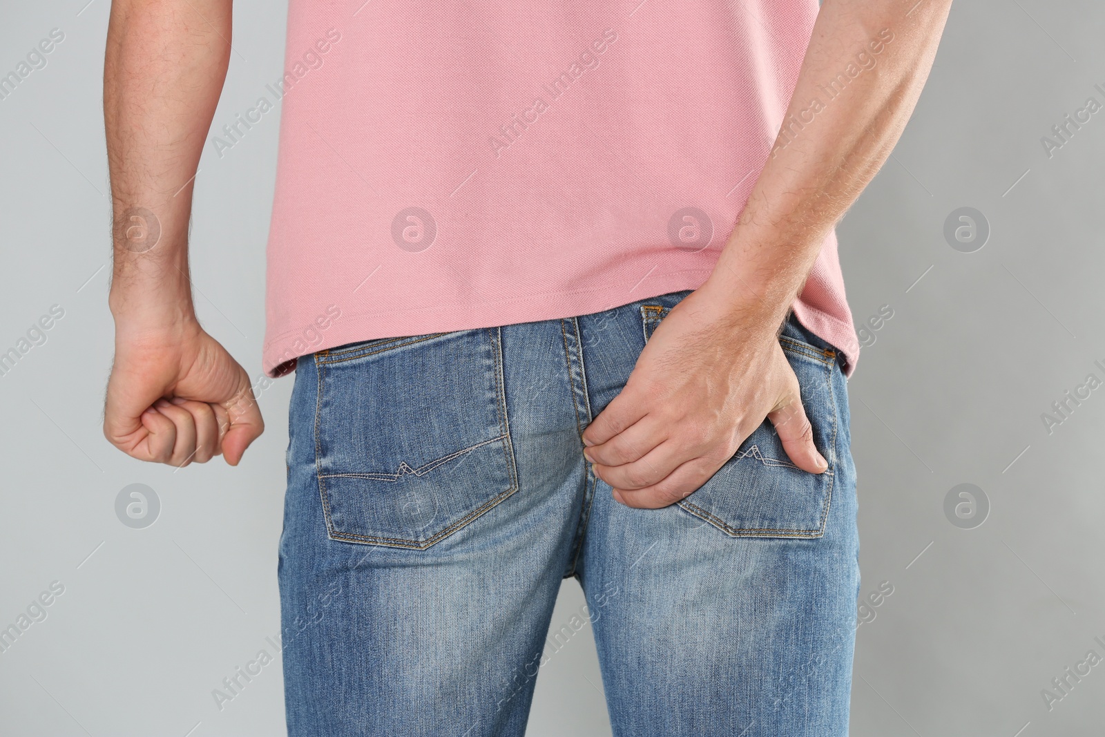 Photo of Man suffering from hemorrhoid on light grey background, closeup