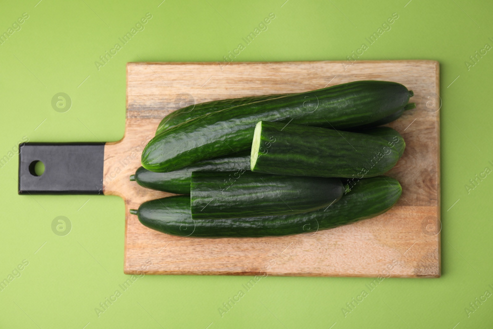 Photo of Fresh cucumbers on green background, top view