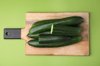 Photo of Fresh cucumbers on green background, top view