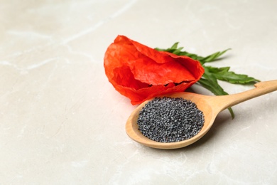 Spoon of poppy seeds and flower on light table, space for text